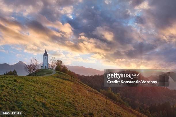 church on the hill during sunrise. gorgeous rising sun with beautiful rays. copy space - steeple stock pictures, royalty-free photos & images