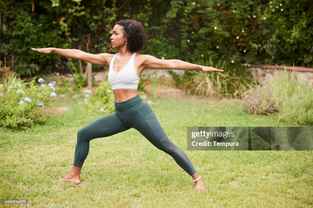 ヴィラバドラサナIIとしても知られるウォリアーツーポーズ、庭に女性のヨガインストラクターがいる