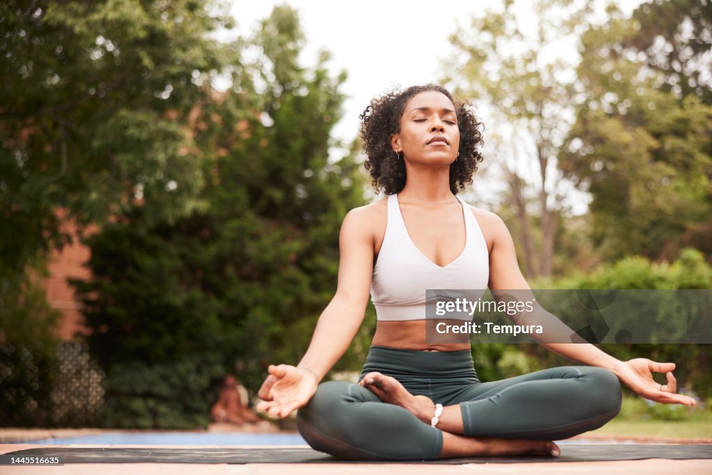 Attractive Afro-American yoga teacher meditating in Lotus Pose