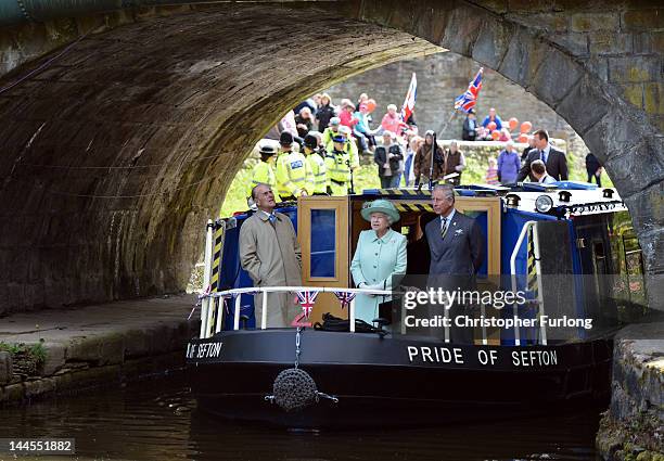 Queen Elizabeth II, Prince Philip, Duke of Edinbugh and Prince Charles, Prince of Wales travel on a canal boat through Burnley town centre as part of...