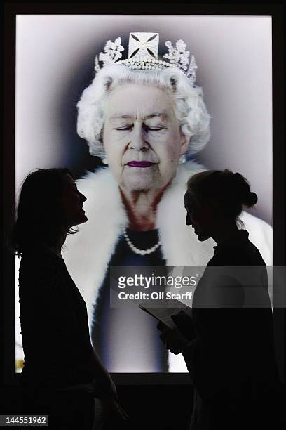 Members of the public view an image of Her Majesty Queen Elizabeth II by artist Chris Levine entitled 'Lightness of Being' in the National Portrait...