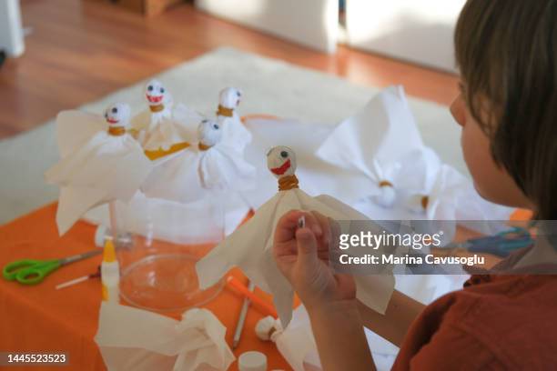 little kid working on fun halloween arts and crafts ghost. - halloween craft stock pictures, royalty-free photos & images
