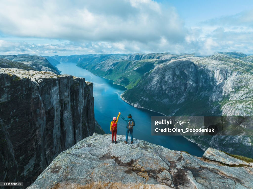 Aerial view of man and woman raising holding arms in mountains in Norway