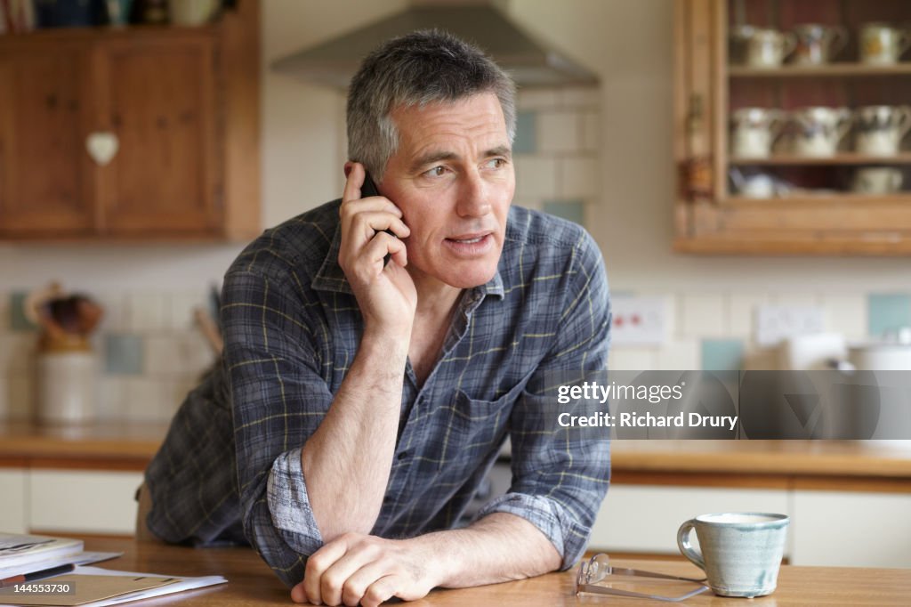 Man using phone in kitchen