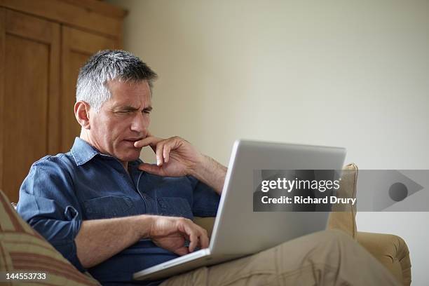 man using laptop on sofa - confused 個照片及圖片檔