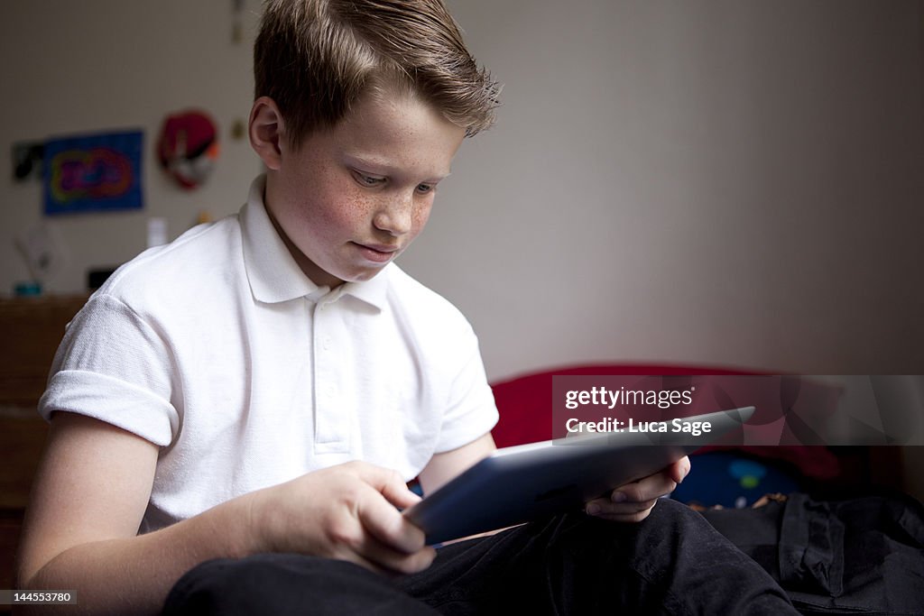 Boy using tablet computer Tablet for homework in his bedroom