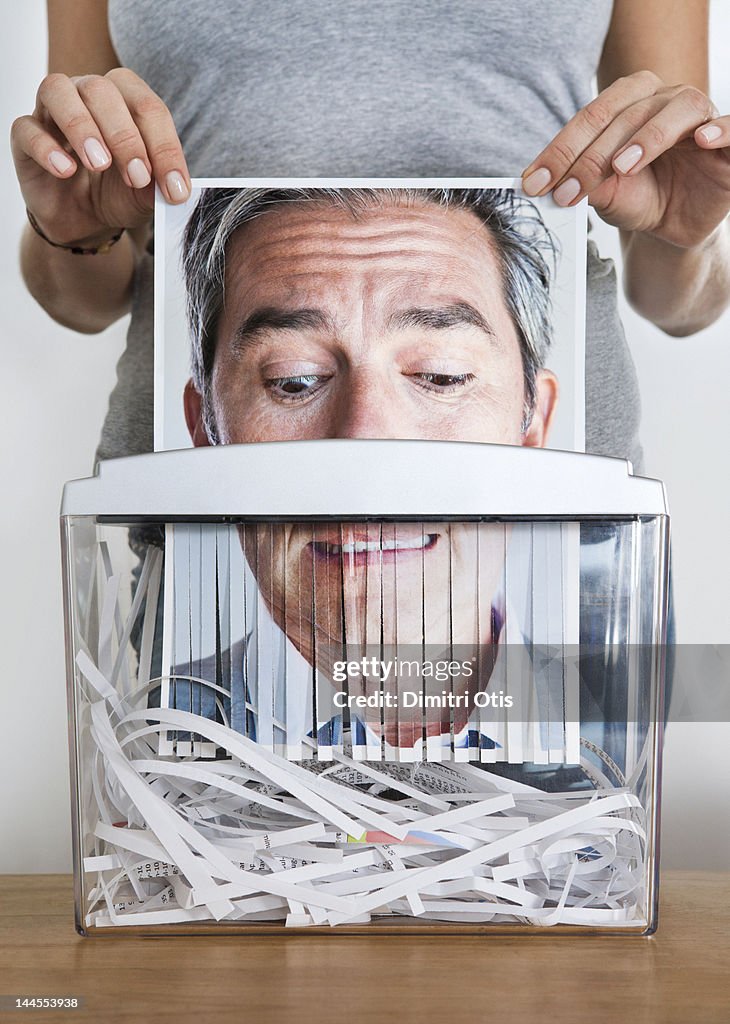 Man's picture being passed through paper shredder