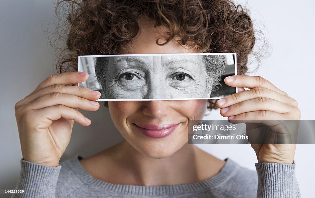 Woman with photo of elderly woman's eyes on hers'