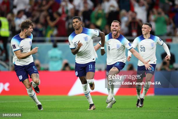 Marcus Rashford of England celebrates with teammates John Stones, Jordan Henderson and Phil Foden after scoring their team's first goal during the...