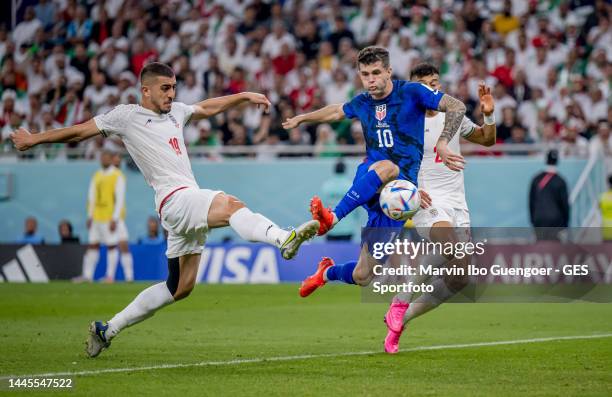 Christian Pulisic of USA scores his team's first goal past Majid Hosseini and Amir Abedzadeh of Iran during the FIFA World Cup Qatar 2022 Group B...