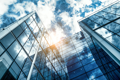 low angle view of a contemporary glass skyscraper reflecting the blue sky