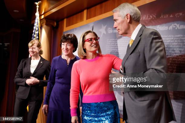 Sen. Kyrsten Sinema pats Sen. Rob Portman during a news conference after the Senate passed the Respect for Marriage Act at the Capitol Building on...