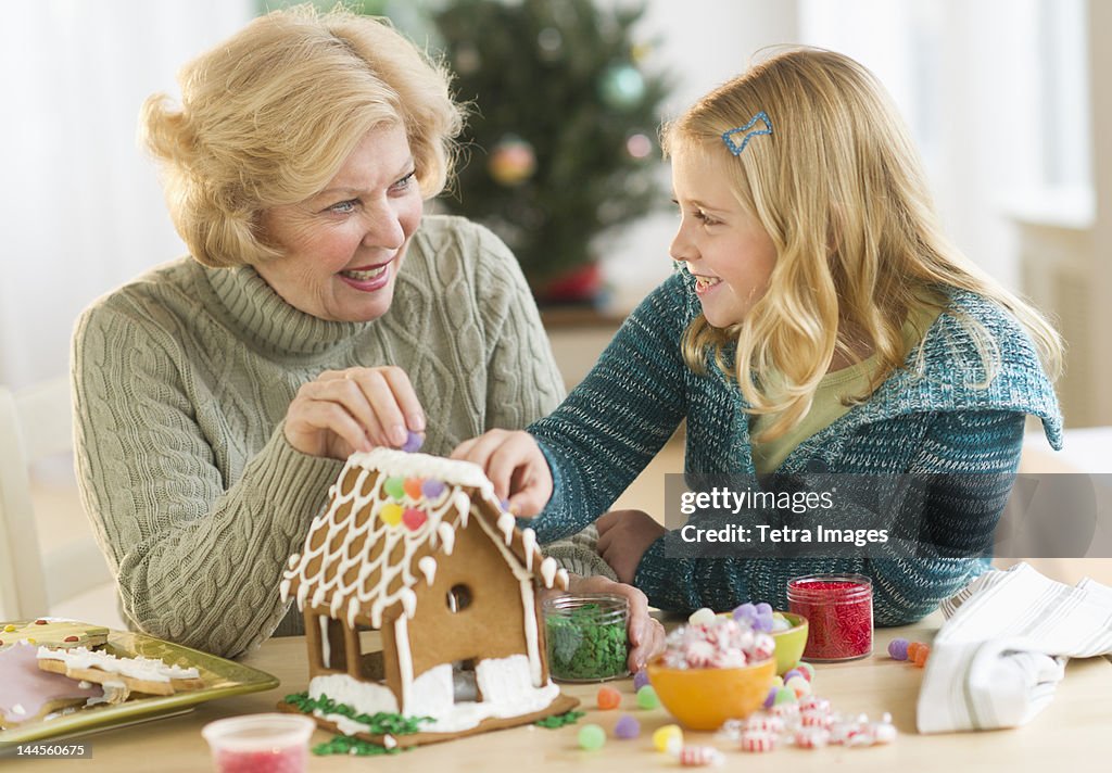 USA, New Jersey, Jersey City, Grandmother with granddaughter (8--9) making gingerbread house