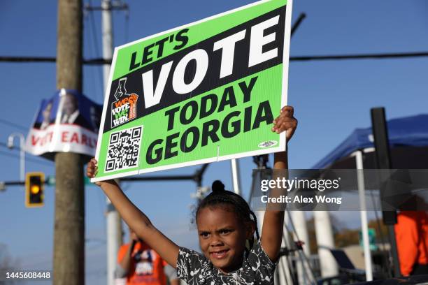 Local resident Reniya Weekes holds a sign to encourage people to vote early outside a polling station on November 29, 2022 in Atlanta, Georgia. Early...