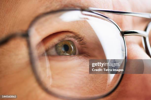 close up of men's eye looking through glasses - occhiali da vista foto e immagini stock