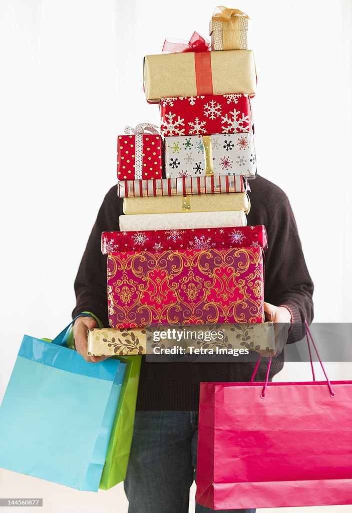 Man carrying stack of Christmas presents, studio shot