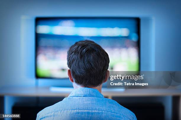 jersey city, new jersey, man watching tv in living room - zusehen stock-fotos und bilder