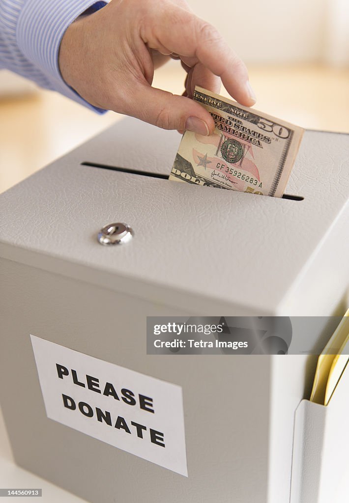 Jersey City, New Jersey, Man's hand  putting dollars into donation box