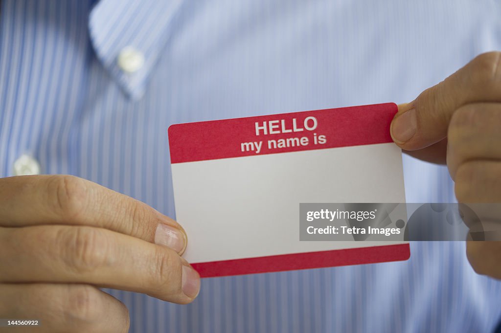 Jersey City, New Jersey, Close up of businessman's hands holding  blank name tag, studio shot
