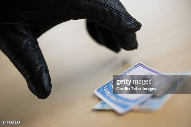close up of thief's hand in black glove stealing driver's license, studio shot - black glove stock pictures, royalty-free photos & images