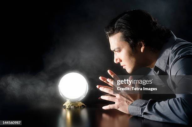 studio shot of businessman looking at crystal ball - 占い師 ストックフォトと画像