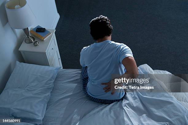 usa, new jersey, jersey city, man sitting on bed - back pain bed stock pictures, royalty-free photos & images