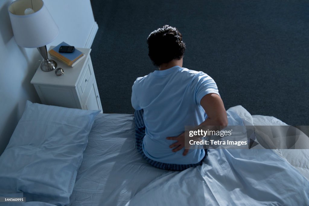 USA, New Jersey, Jersey City, Man sitting on bed