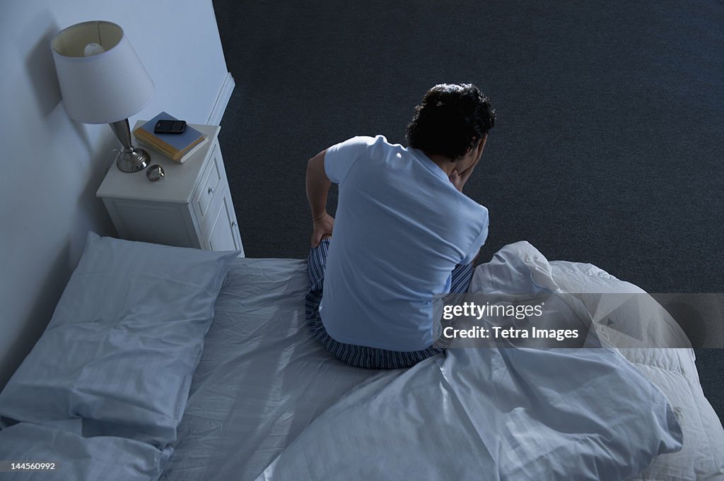 USA, New Jersey, Jersey City, Man sitting on bed
