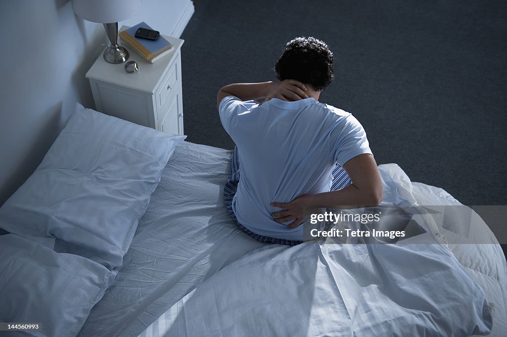 USA, New Jersey, Jersey City, Man sitting on bed