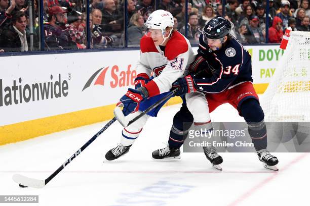 Kaiden Guhle of the Montreal Canadiens controls the puck against Cole Sillinger of the Columbus Blue Jackets during the second period at Nationwide...