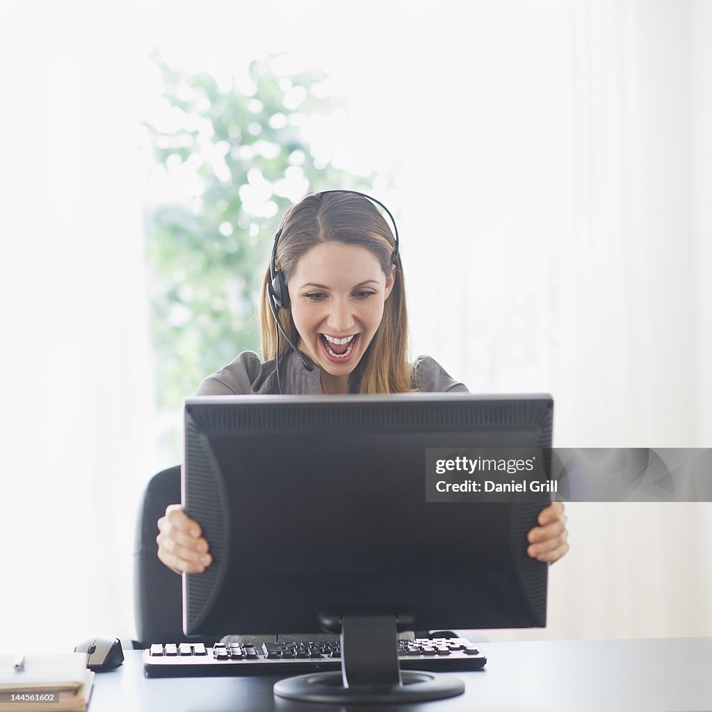 USA, New Jersey, Jersey City, happy young woman holding computer monitor