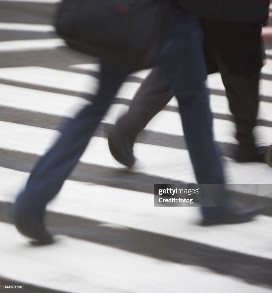 USA, New York state, New York city, low section of men crossing zebra crossing