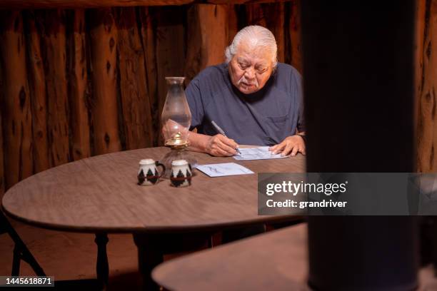 senior man sitting at a table in his hogan,  looking over each candidate, voting their choices and signing the ballot - indigenous american culture bildbanksfoton och bilder