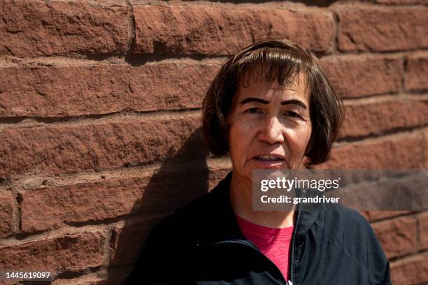 middle aged woman portrait with shallow depth of field on a brick wall - cherokee indian women stockfoto's en -beelden