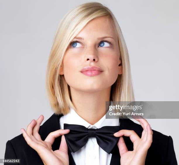 studio portrait of young waitress adjusting bow tie - tuxedo stock pictures, royalty-free photos & images