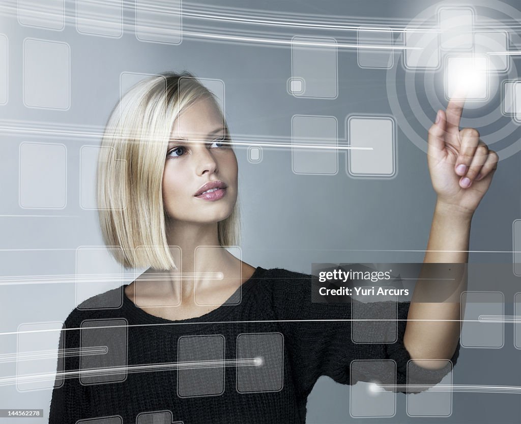 Young woman using futuristic touchscreen, studio shot