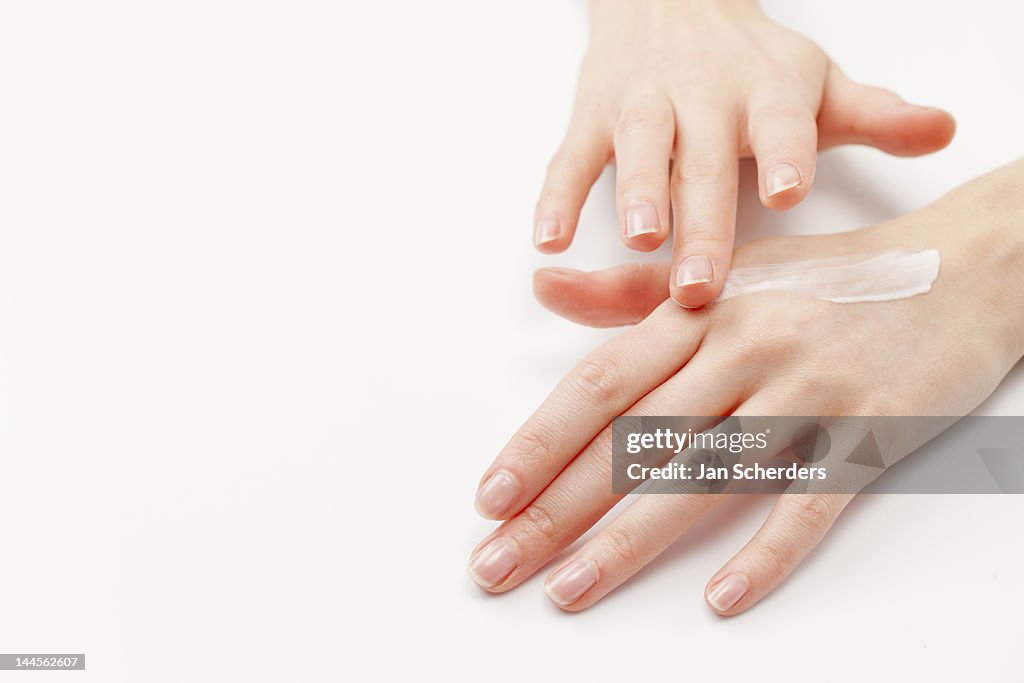 Close up of woman's hands applying  moisturizer, studio shot