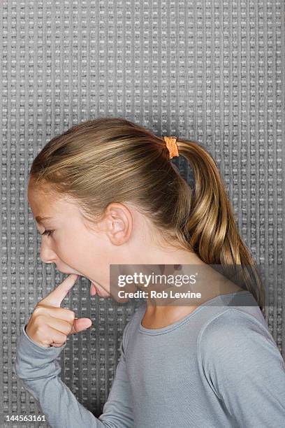 studio portrait of girl (12-13) inserting finger in mouth - erbrechen stock-fotos und bilder