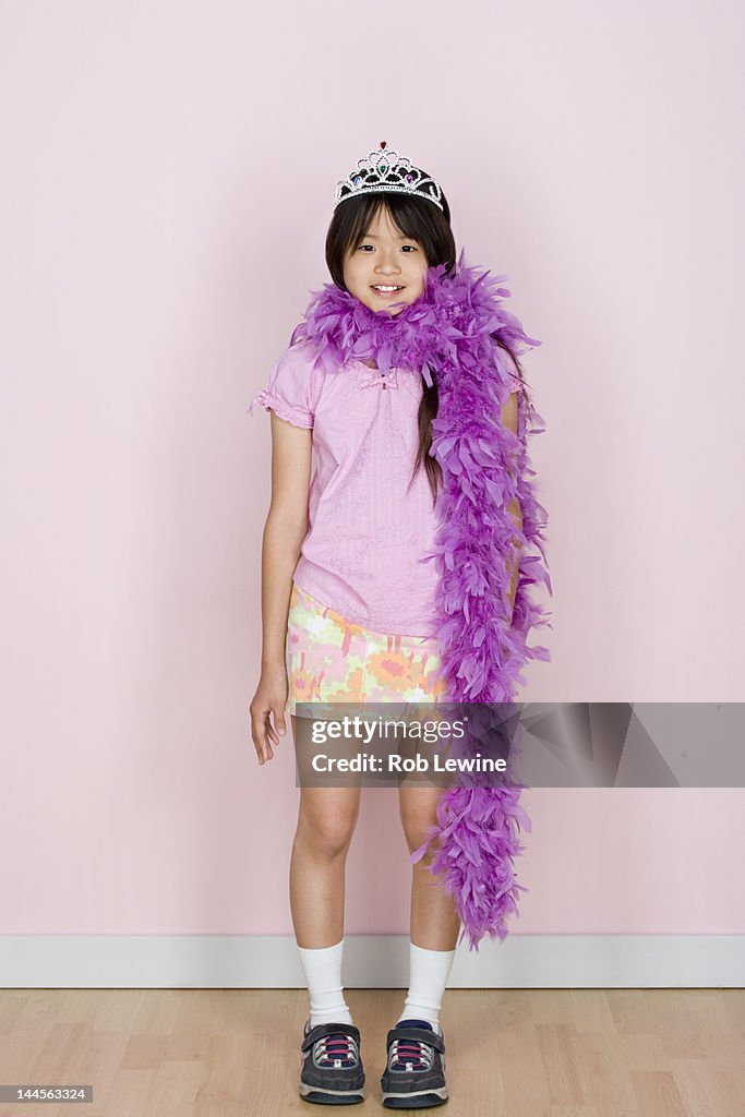 Studio shot portrait of teenage girl in diadem and feather boa shawl, full length