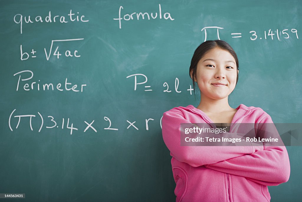 USA, California, Los Angeles, Happy Asian girl standing against blackboard after solving mathematical equation