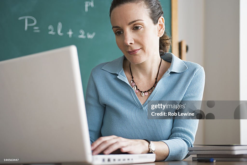USA, California, Los Angeles, Happy female teacher using laptop in classroom
