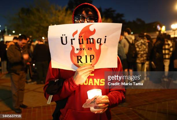 Demonstrator holds a sign reading "Urumqi RIP" sign at a candlelight vigil at University of Southern California honoring those who perished in an...