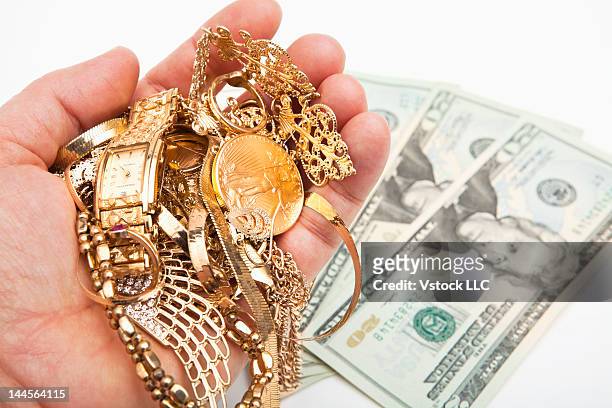 studio shot of male hand holding jewelry over dollar bills - gold hoop earring stockfoto's en -beelden