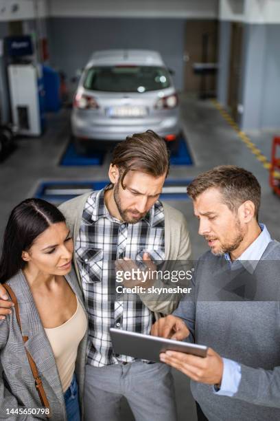 mid adult manager and young couple using touchpad in auto repair shop. - touchpad stockfoto's en -beelden