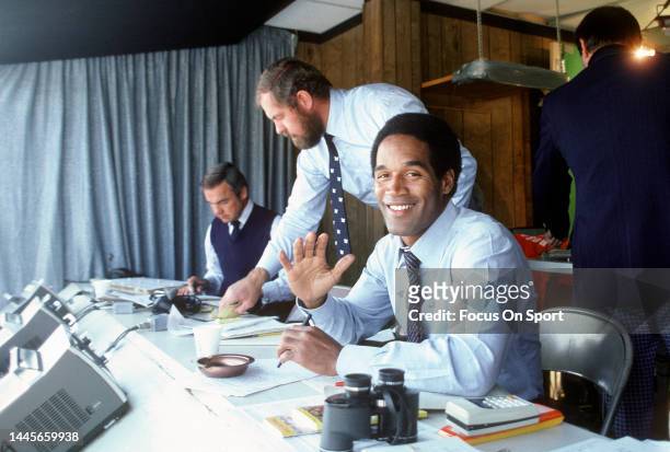 Football Analyst O.J. Simpson in the both smiling for the camera before the start of an NFL football game circa 1980.