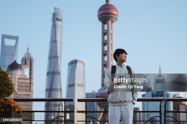 asian man using mobile phone standing in front of oriental pearl tower, shanghai, china - shanghai calling stock pictures, royalty-free photos & images