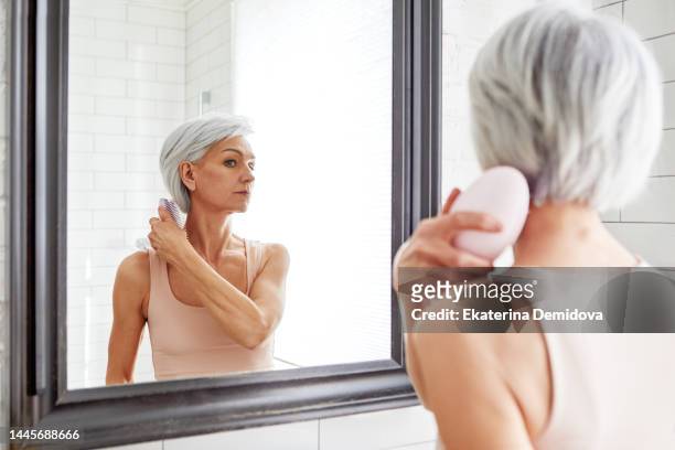 adult beautiful woman combing her hair - kammen stockfoto's en -beelden