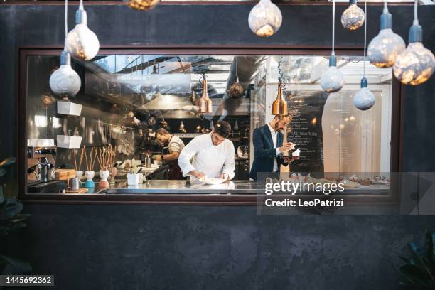 young chef plating and finalizing food in a fine dining luxury restaurant - chef plating stock pictures, royalty-free photos & images