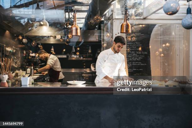 joven chef emplatando y finalizando la comida en un restaurante de lujo de alta cocina - food plating fotografías e imágenes de stock