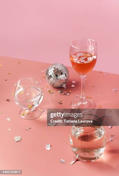 festive layout. xmas feminine party celebration. disco ball, christmas glitter stars and cocktails in glasses on pink background - draft after party stock-fotos und bilder